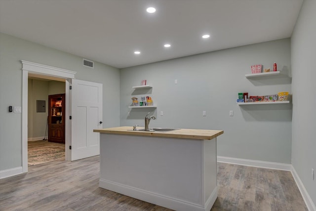 kitchen with butcher block counters, sink, and light hardwood / wood-style flooring