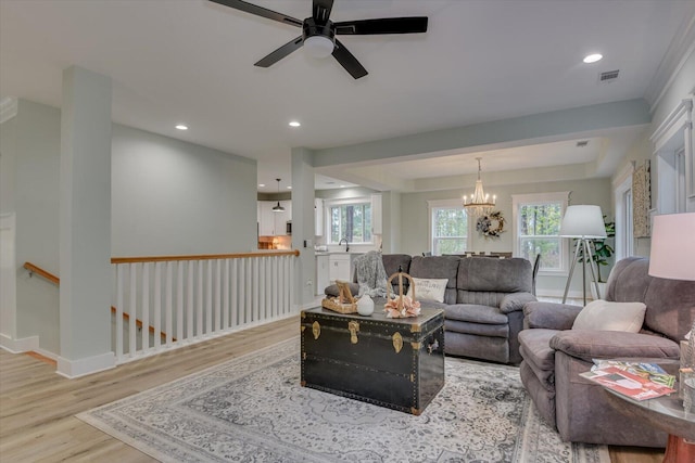 living room featuring ceiling fan with notable chandelier and light hardwood / wood-style floors