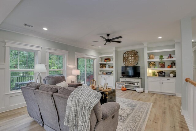 living room featuring ceiling fan, ornamental molding, built in shelves, and light hardwood / wood-style flooring