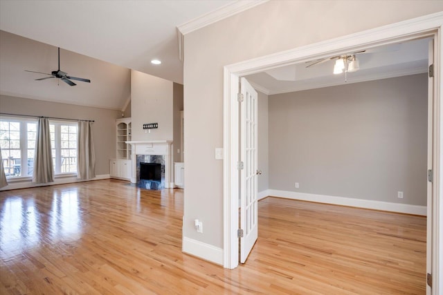 unfurnished living room featuring light wood finished floors, ceiling fan, crown molding, and a high end fireplace