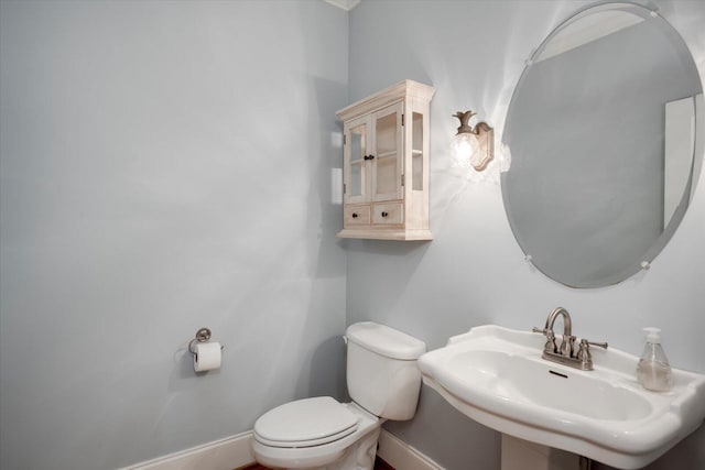 bathroom with toilet, baseboards, and a sink