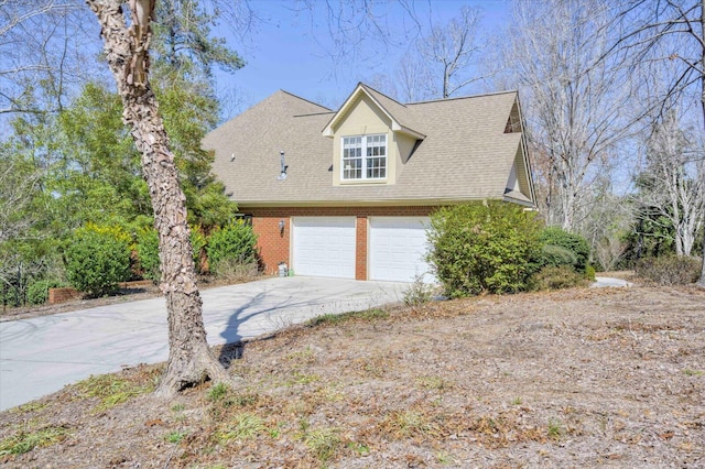 view of front of property featuring a garage, concrete driveway, brick siding, and roof with shingles