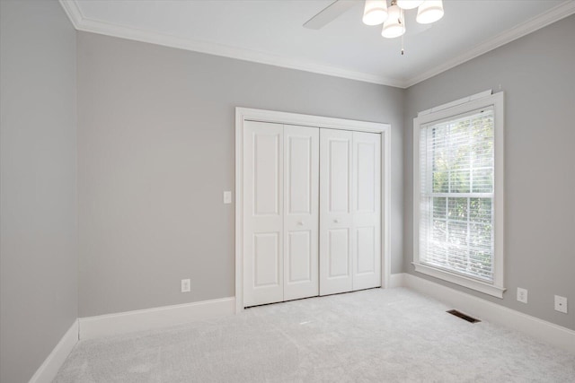 unfurnished bedroom featuring carpet, baseboards, visible vents, and crown molding