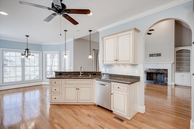 kitchen with light wood-style flooring, stainless steel dishwasher, a premium fireplace, ornamental molding, and a sink