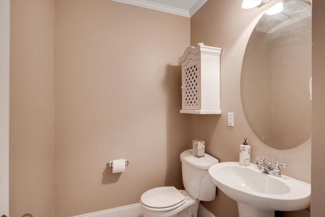 half bath with toilet, crown molding, baseboards, and a sink