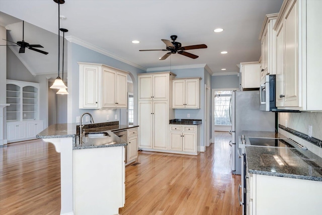 kitchen featuring light wood-style flooring, a peninsula, a breakfast bar, a sink, and stainless steel microwave