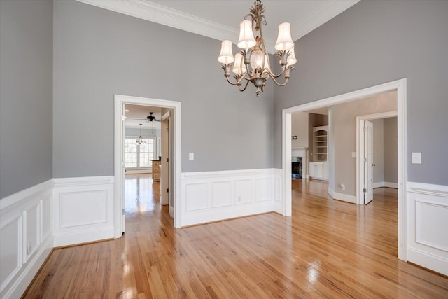 unfurnished dining area with light wood-type flooring, a fireplace, and ornamental molding