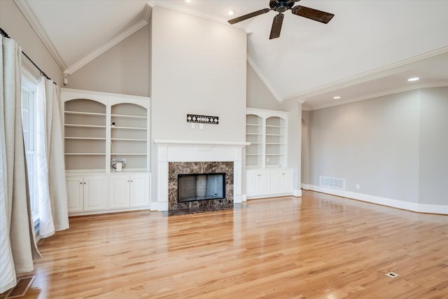 unfurnished living room featuring light wood-style flooring, a premium fireplace, visible vents, and a ceiling fan