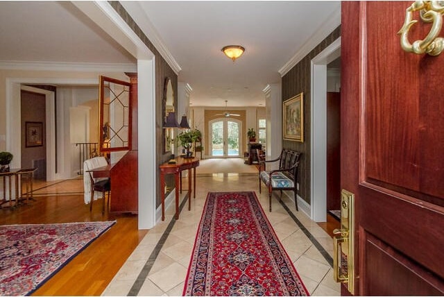 corridor with french doors, light tile patterned floors, and ornamental molding