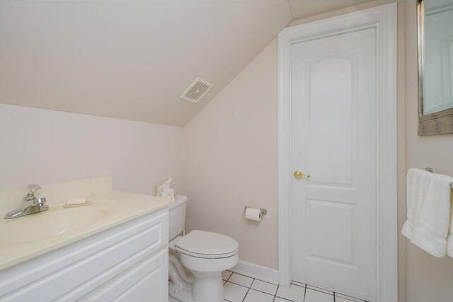 bathroom with tile patterned flooring, vanity, toilet, and vaulted ceiling