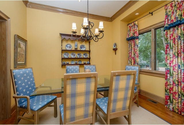 dining room with a chandelier, wood-type flooring, and crown molding