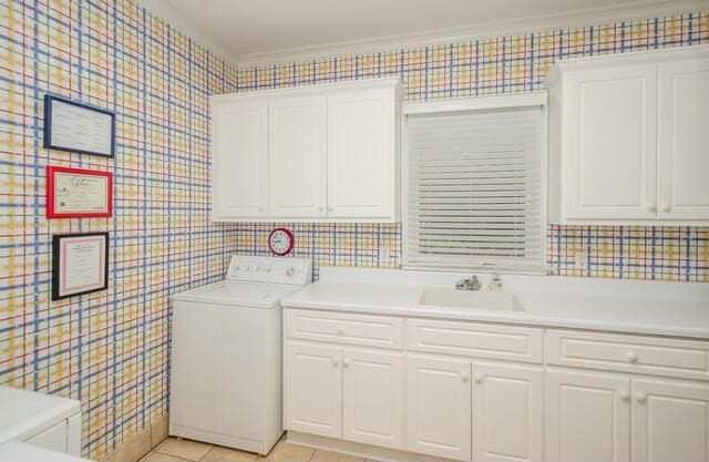 laundry area with cabinets, light tile patterned floors, crown molding, and washer / clothes dryer