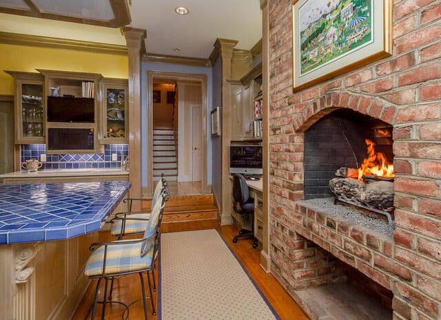 interior space with tasteful backsplash, a brick fireplace, crown molding, light hardwood / wood-style floors, and tile counters