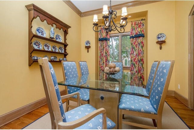 dining room featuring ornamental molding, wood-type flooring, and a notable chandelier