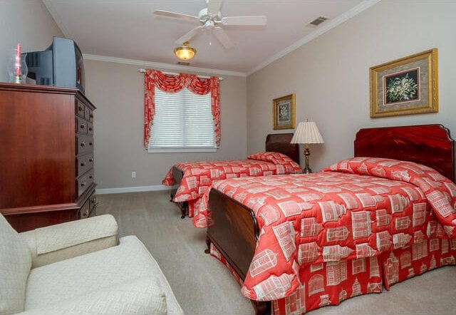 carpeted bedroom featuring ceiling fan and crown molding