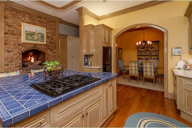 kitchen featuring ornamental molding, tile counters, black appliances, and an inviting chandelier