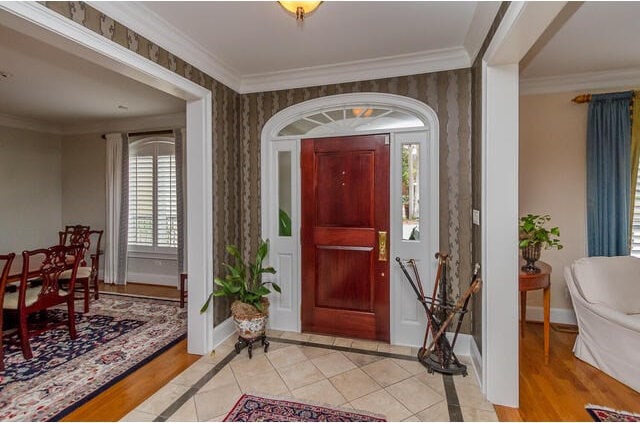 foyer entrance with ornamental molding and light tile patterned flooring