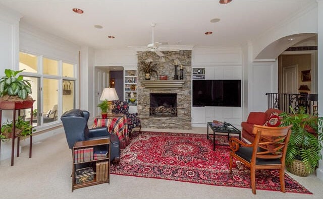 carpeted living room featuring ceiling fan, a fireplace, and crown molding