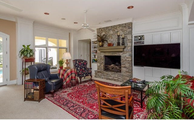 living room featuring a fireplace, light carpet, ceiling fan, and ornamental molding