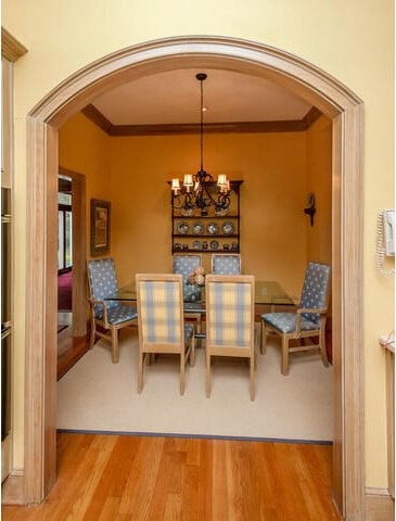 dining area with light wood-type flooring, crown molding, and a chandelier