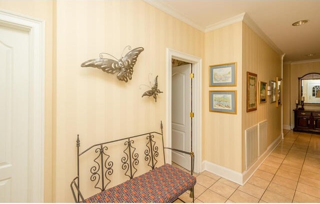 hallway featuring ornamental molding and light tile patterned floors