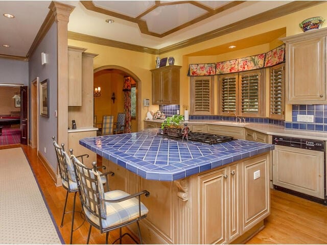 kitchen featuring a center island, light hardwood / wood-style floors, tile counters, and ornamental molding