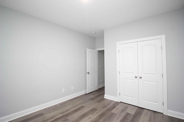 unfurnished bedroom with wood finished floors, a closet, and baseboards
