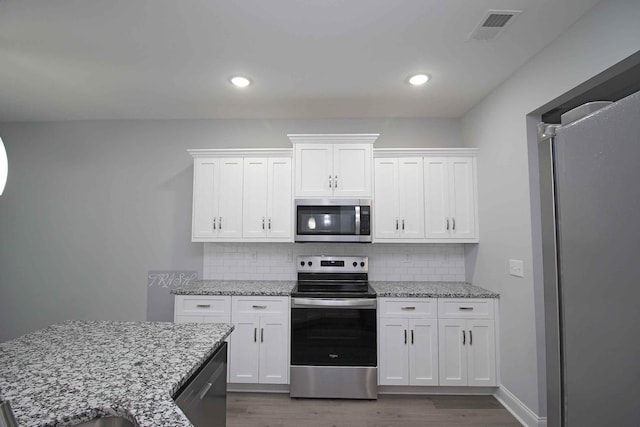 kitchen with appliances with stainless steel finishes, dark wood-type flooring, white cabinetry, tasteful backsplash, and recessed lighting