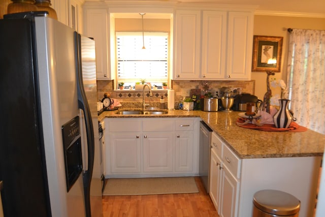 kitchen featuring appliances with stainless steel finishes, crown molding, sink, white cabinets, and hanging light fixtures