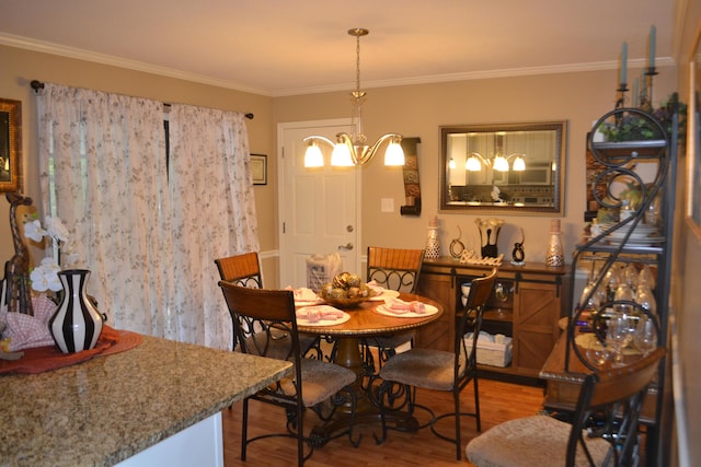 dining space with hardwood / wood-style floors, ornamental molding, and a chandelier