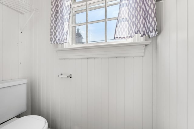 bathroom with wood walls and toilet