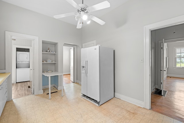 interior space featuring ceiling fan, white fridge with ice dispenser, stacked washing maching and dryer, a closet, and light wood-type flooring