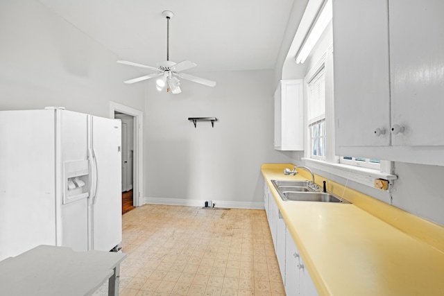 kitchen with white refrigerator with ice dispenser, white cabinetry, ceiling fan, and sink