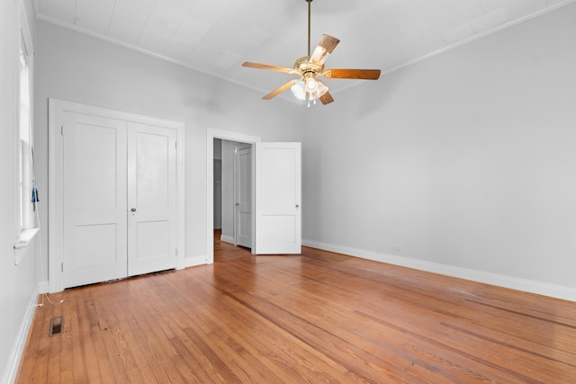 unfurnished bedroom featuring hardwood / wood-style floors, ceiling fan, ornamental molding, and a closet