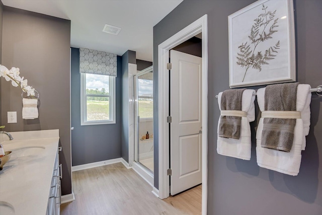 bathroom with vanity, hardwood / wood-style floors, and a shower with door