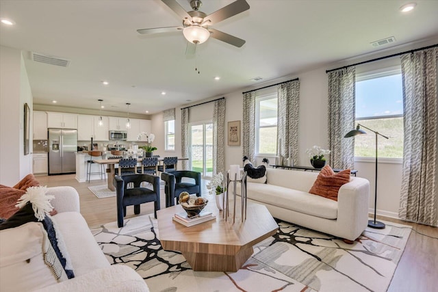 living room featuring ceiling fan, a wealth of natural light, and light hardwood / wood-style floors