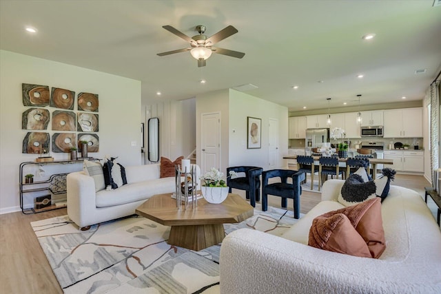 living room with ceiling fan and light hardwood / wood-style flooring