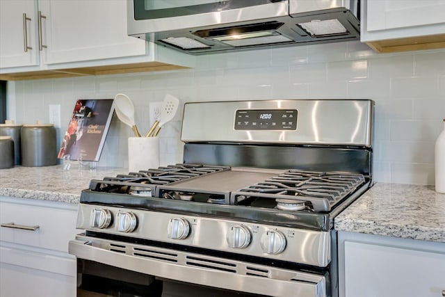 details with white cabinets, decorative backsplash, light stone counters, and gas stove