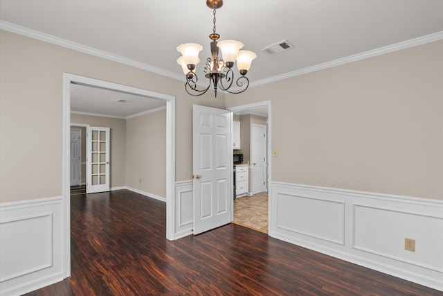 unfurnished dining area with a notable chandelier, ornamental molding, and dark wood-type flooring