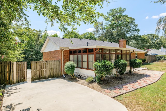 rear view of property featuring a sunroom and a lawn