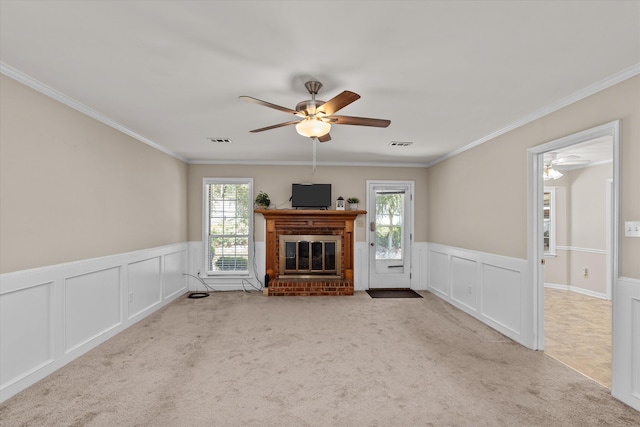 unfurnished living room with light carpet, ceiling fan, ornamental molding, and a brick fireplace