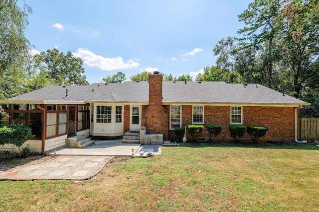 rear view of property featuring a sunroom, a yard, and a patio