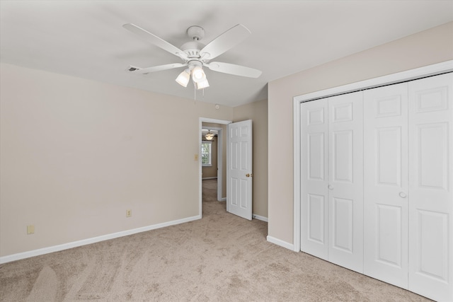 unfurnished bedroom featuring light carpet, a closet, and ceiling fan