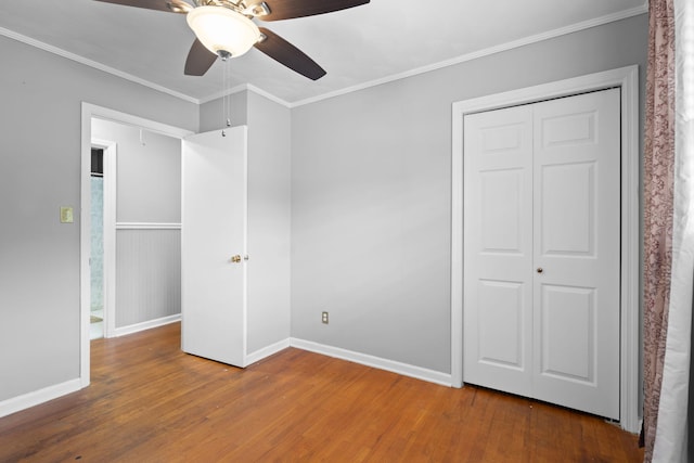 unfurnished bedroom with a closet, hardwood / wood-style flooring, ceiling fan, and crown molding