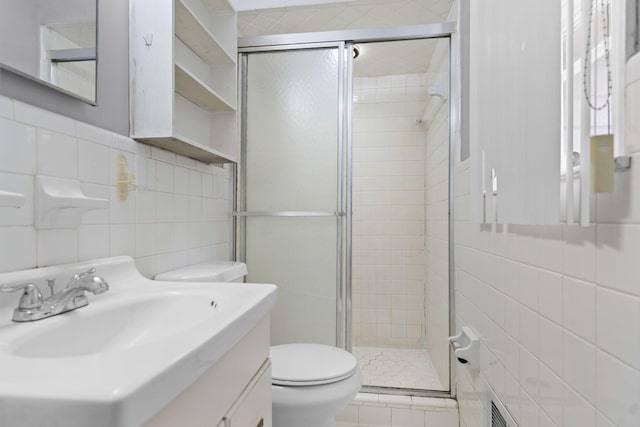 bathroom featuring vanity, toilet, an enclosed shower, and tile walls