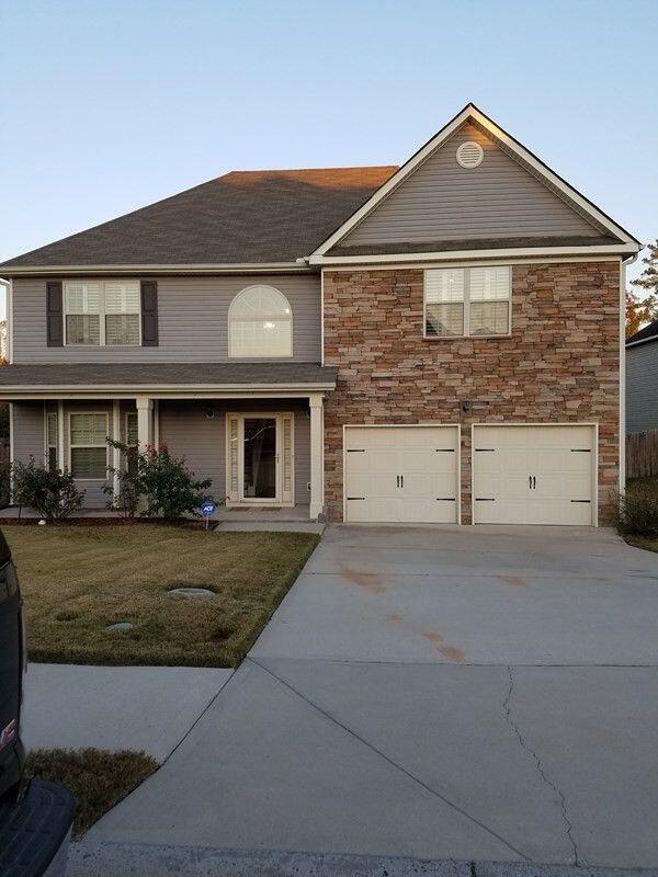 traditional-style home featuring a garage, concrete driveway, stone siding, and a front yard