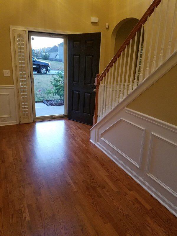 foyer featuring arched walkways, a wainscoted wall, stairway, wood finished floors, and a decorative wall