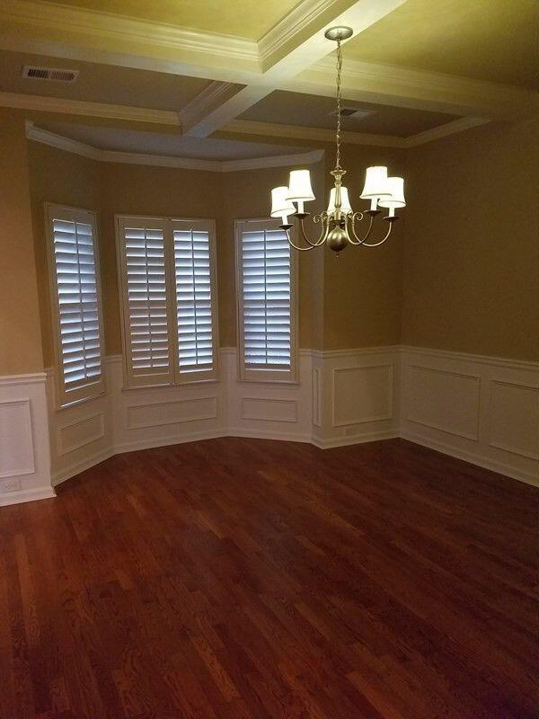 empty room featuring dark wood-style floors, a wainscoted wall, a notable chandelier, crown molding, and visible vents