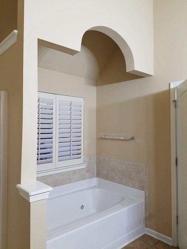 bathroom with a garden tub and baseboards