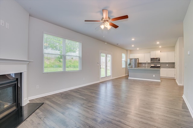 6093 Whitewater Dr, North Augusta, SC 29841 - unfurnished living room featuring light wood finished floors, a glass covered fireplace, a ceiling fan, and recessed lighting